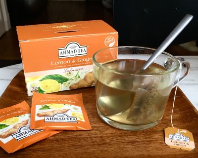 Tasse, infusion, paquet de tisane et sachets sur un plateau en bois.